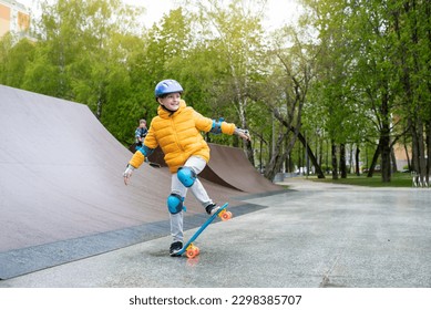 a child rides a blue city cruiser, a plastic bright skateboard, in a skate park on a halfpipe - Powered by Shutterstock