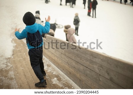 Child rides down slide. Winter game. Boy rides on his feet on ice. Winter entertainment.