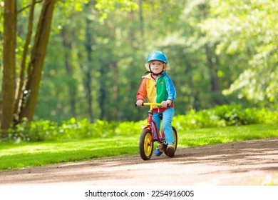 Child riding balance bike. Kids on bicycle in sunny park. Little boy enjoying to ride glider bike on warm summer day. Preschooler learning to balance on run bicycle in safe helmet. Sport for kids. - Shutterstock ID 2254916005