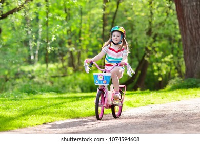 Child Riding A Bike In Summer Park. Little Girl Learning To Ride A Bicycle Without Training Wheels. Kindergarten Kid On Two Wheeler Bike. Active Outdoor Sport For Kids. Children Cycling.