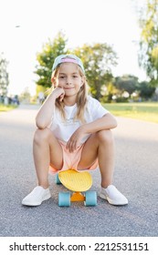 Child Riding Skateboard In Summer Park. Little Girl Learning To Ride Skate Board. Active Outdoor Sport For School And Kindergarten Kids. Children Skateboarding. Preschooler Sitting On Skateboard.