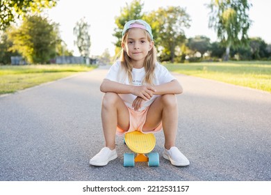 Child Riding Skateboard In Summer Park. Little Girl Learning To Ride Skate Board. Active Outdoor Sport For School And Kindergarten Kids. Children Skateboarding. Preschooler Sitting On Skateboard.