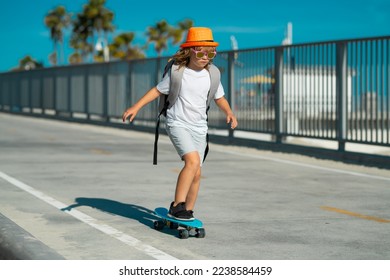 Child riding skateboard in summer park. Little boy learning to ride skate board. Active outdoor sport for kids. Children skateboarding. Kid ride on skateboard. Lets ride. Child on skateboard skating.