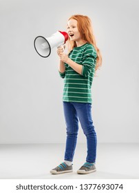 Child Rights, Communication And People Concept - Smiling Red Haired Girl In Green Striped Shirt And Jeans Speaking To Megaphone Over Grey Background