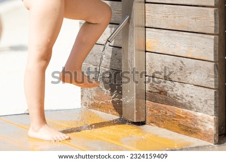 Child rinsing off his feet and shoes to get rid of the salt and sand after spending the day at the beach at a seaside resort on summer vacation