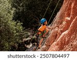 child is rock climbing at a summer camp. rock climber boy. sport in nature. cute teenager climbs a rock with a belay. active holidays. summer rest.