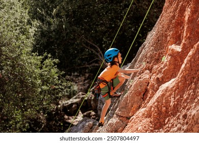 child is rock climbing at a summer camp. rock climber boy. sport in nature. cute teenager climbs a rock with a belay. active holidays. summer rest. - Powered by Shutterstock