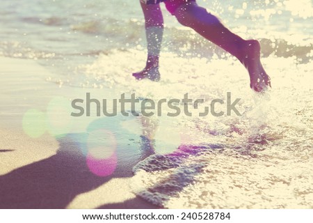 Child running at the beach, runner has motion blur. Focus on sand