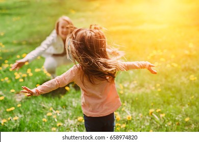 Child running into mother's hands to hug her. Family having fun in the park. Girl is happy to meet her mom. Background image. - Powered by Shutterstock