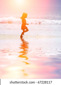 Child Running On Water At Ocean Beach At Sunset.