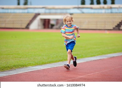 Child Running In Stadium. Kids Run On Outdoor Track. Healthy Sport Activity For Children. Little Boy At Athletics Competition Race. Young Athlete In Training. Runner Exercising. Jogging For Kid.