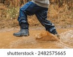 A child is running through a muddy puddle. The water is brown and the child