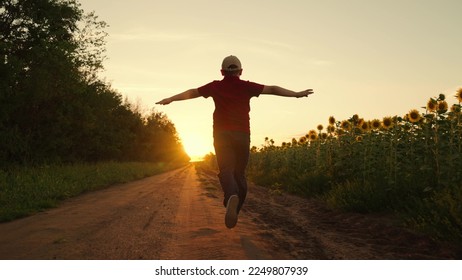 Child runs with his arms raised like wings of an airplane, childhood dream travel, nature. Silhouette of boy running at sunset, child pilot runs through field of sunflowers, kid dreams, airplane pilot - Powered by Shutterstock