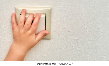 Child S Hand Presses The Light Switch, Copy Space. Toddler Baby Boy Turns On The Lamp In The Room. Kid Aged One Year And Three Months