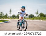 Child in safety helmet riding bike. Boy riding bike wearing a helmet outside. Child in safety helmet riding bike. Little kid boy learns to ride a bike. Kid on bicycle. Happy child in helmet riding a