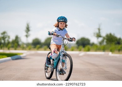 Child in safety helmet riding bike. Boy riding bike wearing a helmet outside. Child in safety helmet riding bike. Little kid boy learns to ride a bike. Kid on bicycle. Happy child in helmet riding a