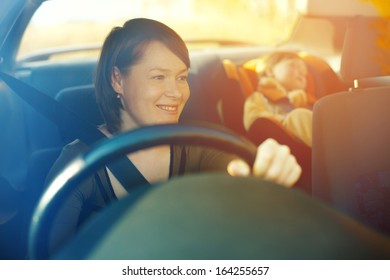 The child in a safety seat near to mother who sits on forward sitting of the car.