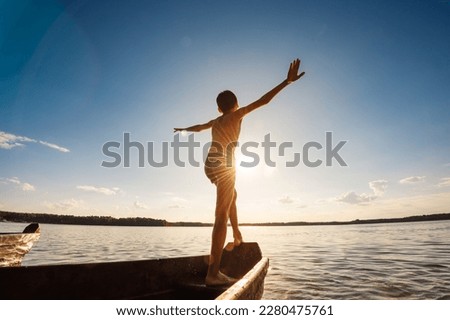 Child is sailing on a boat at sunset. Active rest at sea in summer.