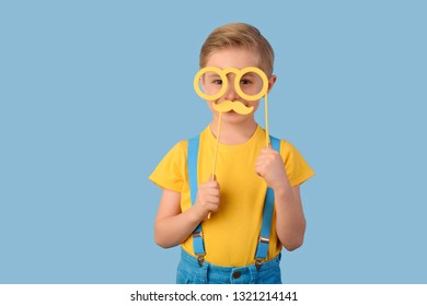 Child, sale, spring. Child in yellow,  blue colors, he has yellow glasses and a mustache near his face.   Photo both props. Waist up, thin, facing camera, studio, blue background. - Powered by Shutterstock