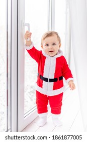 Child In Santa Suit On The Sill Of The Window, The Concept Of New Year And Christmas