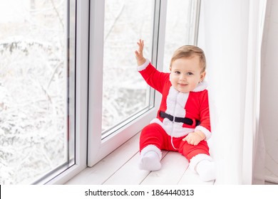 Child In Santa Suit On The Sill Of The Window, The Concept Of New Year And Christmas