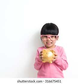 Child Savings, Investment Or Money Concept Illustrated With Asian Kid Holding A Piggy Bank