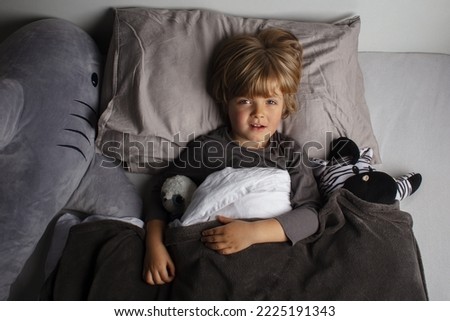 The child was scared before going to bed. Night terrors in a child. r. Children's experiences. Boy in the bed. View from above. Sad psychological state. Bad mood before a sleeping.