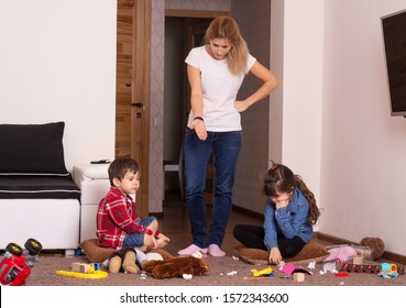Child scattered toys. Mess in the house. Children play and do not obey mother. 