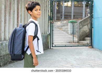 Child At The School Gate For The Start Of School, Turns And Looks At His Parents. Back To School Concept. High Quality Photo