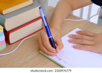 child, schoolboy 9-10 years, primary school student writes in notebook, Back to school concept, children's hand close-up, doing homework in foreign language, spelling skills, intense school load