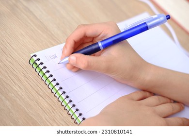 child, schoolboy, writes words, letter to friend in English in a notebook with pen, education concept, elementary school, hand development, chatting with a distant pen pal, Back to school