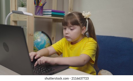 Child Schoolgirl Typing On Laptop Keyboard At Home, Online Child Game. School Class Lesson Kid Online, Little Daughter Works Control Remotely. Children Typing Laptop Keyboard While Sitting At Home