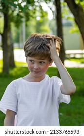 The Child Scratches His Head. A Boy With Long Thick Hair Has An Itchy Head Due To Dandruff. 