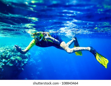 Child Scuba Diver With Group Coral Fish In  Blue Water.