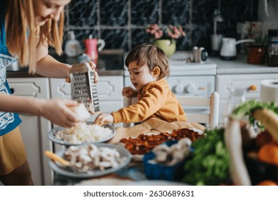 Un niño sentado en una mesa en una cocina ayudando a sus padres a preparar una comida usando alimentos e ingredientes frescos, fomentando un vínculo y promoviendo el trabajo en equipo en la cocina.