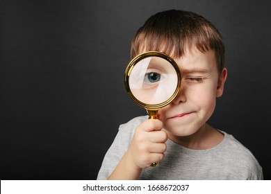 Child See Through Magnifying Glass On The Black Backgrounds. Big Kid Eye