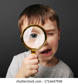 Child See Through Magnifying Glass On The Black Backgrounds. Big Kid Eye