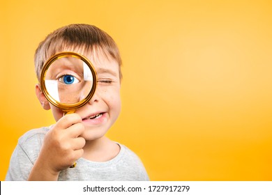 Child see through magnifying glass on the color yellow backgrounds. Big kid eye