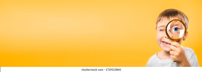 Child see through magnifying glass on the color yellow backgrounds. Big kid eye