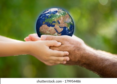 Child and senior man holding Earth in hands against green spring background. Elements of this image furnished by NASA - Shutterstock ID 179954486
