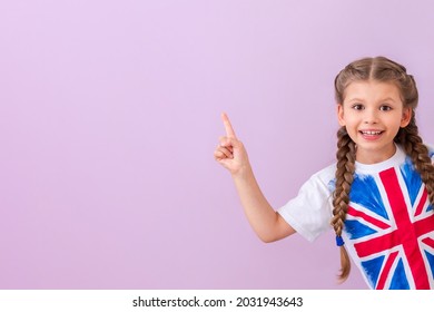 A child in a shirt with a British flag points to your ad on an isolated pink background. - Shutterstock ID 2031943643