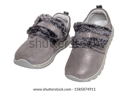 Child shoes fashion. Close-up of a pair beautiful gray silver suede sneaker or sports shoes for girls with fur and rhinestone decoration isolated on a white background. Macro of kids trendy footwear.