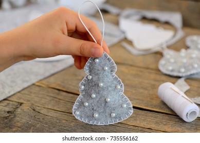 Child shows a felt Christmas tree toy. Child holds a Christmas tree toy in his hand. Child made a Christmas ornament from felt. Easy winter crafts and activities for preschoolers