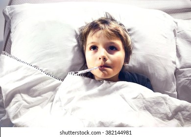 Child Sick In Bed With Fever And Thermometer