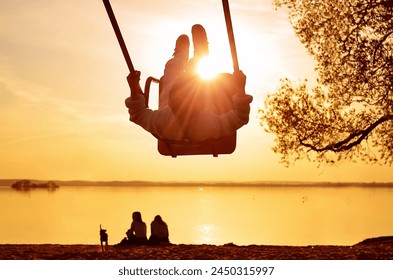 Child silhouette swinging on a swing at sunset on the beach - Powered by Shutterstock