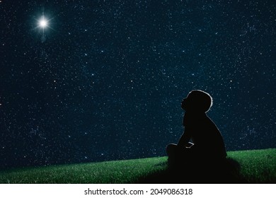 child sit on the grass at night and look at the night sky