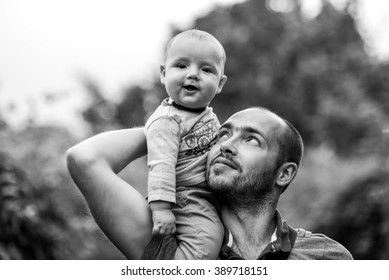 child sits on dad's shoulder and smiling. black and white a photo