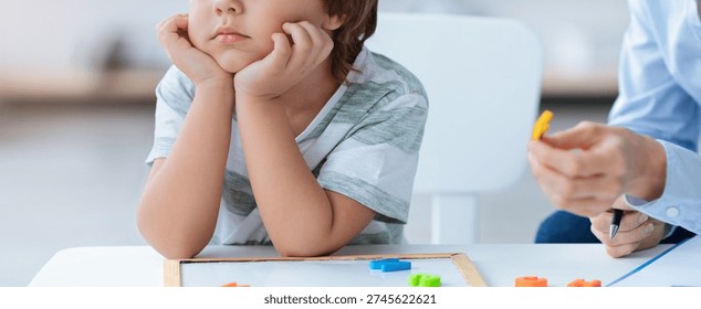 Child Sits at Table With Learning Tools While Adult Engages in Educational Activity
