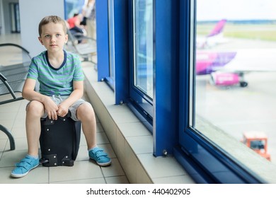 Child sitting at bag at the airport and waiting for his plane