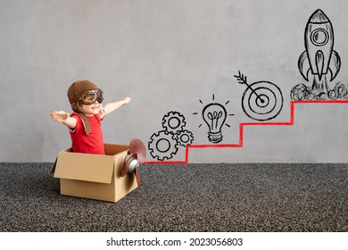 Child Sitting In Cardboard Box. Kid Having Fun At Home. Child Playing. Kid Pretend To Be Pilot. Career Development And Education Concept